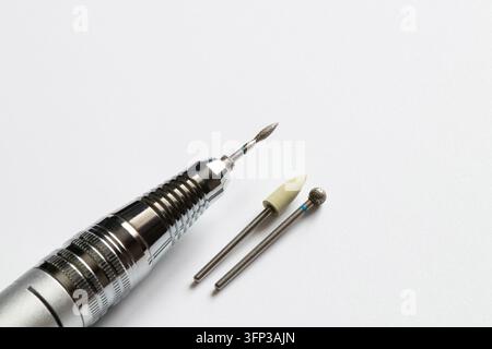 Set de manucure avec une perceuse à ongles électrique et des accessoires sur fond blanc. Outils de soin des ongles et de manucure Banque D'Images