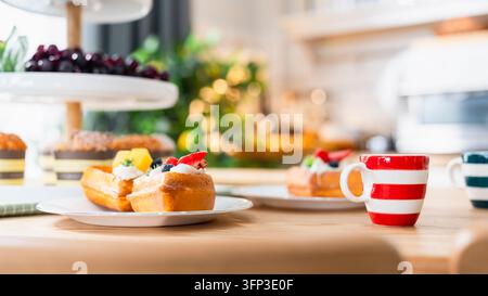 Dessert de gaufre fraîchement cuit et concept de petit-déjeuner en café, gaufres croustillantes recouvertes de crème fouettée et de baies dans une assiette à côté d'une tasse à café rayée Banque D'Images