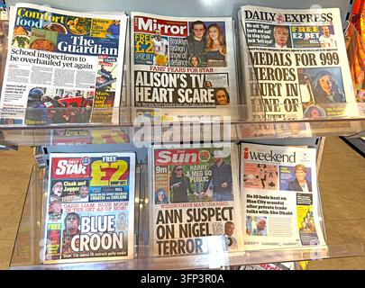 Un assortiment de journaux britanniques est étalé sur un kiosque, comprenant des titres de tabloïd et du marché moyen avec de gros titres. Banque D'Images