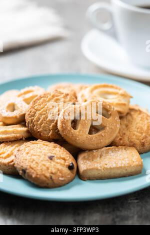 Divers biscuits au beurre sur une assiette avec une tasse de café sur une table en bois Banque D'Images