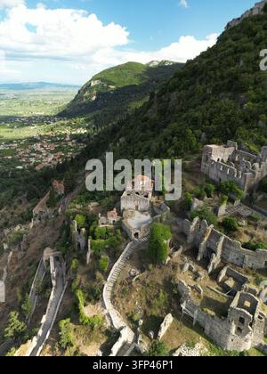 Prise de vue verticale en drone à angle élevé montrant des ruines de château en pierre, des chemins et une végétation luxuriante sur une colline escarpée grecque. Banque D'Images