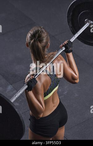 Close-up d'un modèle fitness attrayant s'entraînant avec des haltères Femme sportive aux épaules, biceps et triceps parfaits Photo verticale Banque D'Images