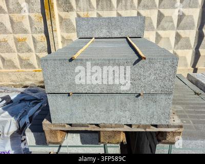 Une grande pile de dalles de pavage en béton gris est soigneusement disposée sur une palette en bois, prête pour des projets de construction ou d'aménagement paysager Banque D'Images