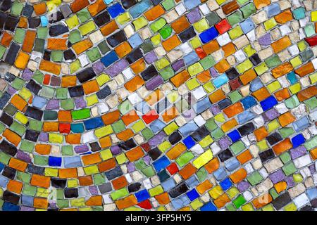 Motif mosaïque abstrait coloré composé de petits carreaux de verre irréguliers, surface décorative vibrante avec des lignes courbes et une texture géométrique multicolore. Banque D'Images