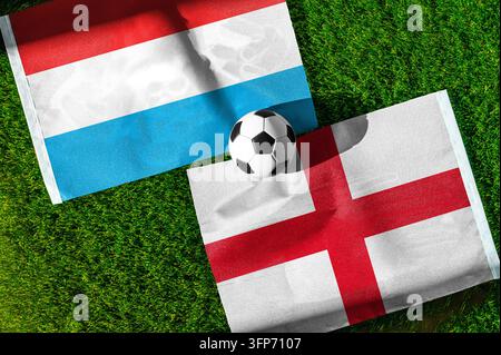 Match de football Luxembourg contre Angleterre. Drapeaux nationaux sur l'herbe verte avec un ballon de football au centre. Fond de football pour un match international. Banque D'Images