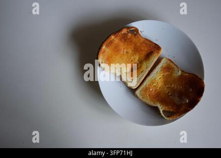Toast doré avec du beurre sur une assiette positionnée en diagonale Banque D'Images