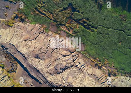 Vue aérienne abstraite d'une frontière environnementale forte. Les déchets industriels intensément érodés (détails) contrastent fortement avec les zones humides luxuriantes, représentent Banque D'Images