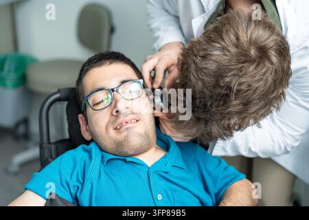 Docteur examinant l'oreille d'un patient avec un otoscope lors d'un examen médical pour des soins de santé inclusifs Banque D'Images