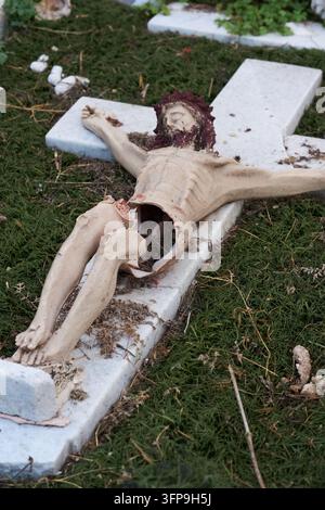Statue de crucifix brisée gisant sur une croix en marbre dans un vieux cimetière mexicain, Monterrey, Mexique Banque D'Images