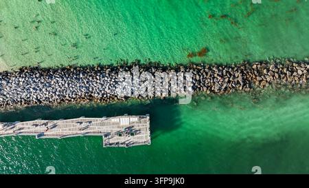 Vue aérienne du quai en pierre Government Cut et du ponton en bois entourés d'eau turquoise avec des gens qui nagent et marchent sur le ponton à Miami-Dade Banque D'Images