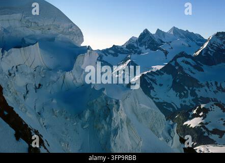 Une vue aérienne à couper le souffle met en valeur un vaste système glaciaire avec des pics imposants. La scène capture la beauté brute et l'échelle de l'environnement des hautes Alpes Banque D'Images