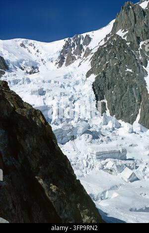 Une vue aérienne époustouflante met en scène un glacier massif descendant des sommets enneigés. La scène capture la beauté brute et l'échelle des Alpes de haute altitude Banque D'Images
