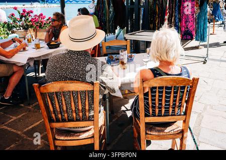 Touristes se relaxant dans un café en bord d'eau à côté d'étals de marché colorés à Katakolo, en Grèce occidentale. Banque D'Images
