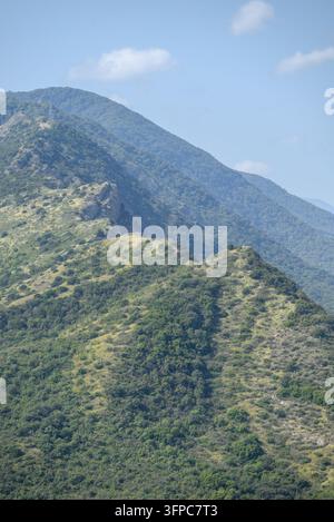 Une vue panoramique époustouflante mettant en valeur la beauté sauvage d'une chaîne de montagnes sous un soleil éclatant, capturant une végétation luxuriante et des formations rocheuses exposées Banque D'Images