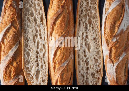 Baguettes françaises fraîchement cuites entières et coupées en deux en arrière-plan Banque D'Images