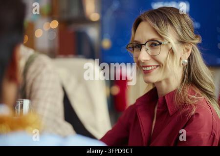 Femme souriante discutant avec des collègues lors d'une célébration au bureau Banque D'Images