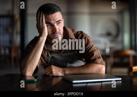Entrepreneur masculin stressé tenant sa tête dans les mains à cause d'un échec professionnel ou d'un burn-out Banque D'Images