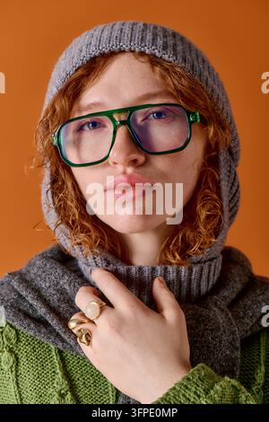 Une jeune et belle femme met en valeur ses cheveux bouclés et ses vêtements d'hiver, se sentant au chaud et à la mode. Banque D'Images