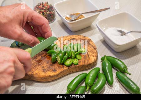 Des poivrons jalapeno verts frais sont coupés pour la conservation en saumure, avec du sel, des graines de fenouil et des poivrons mélangés préparés comme ingrédients pour fait maison Banque D'Images
