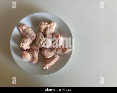 Ailes de poulet crues sur une assiette blanche avec espace libre Banque D'Images