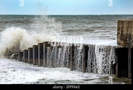 Les vagues de tempête s'écrasent sur un brise-lames côtier, démontrant la puissance destructrice de l'eau de mer et son rôle dans l'érosion côtière Banque D'Images