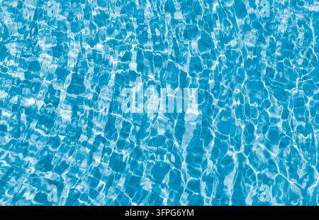Surface d'eau bleue cristalline d'une piscine avec des caustiques ondulantes et des reflets ensoleillés créant un fond de vacances d'été rafraîchissant avec copie Banque D'Images