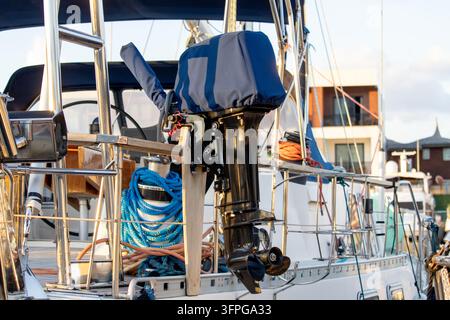Gros plan d'un moteur hors-bord auxiliaire monté sur la rambarde de poupe d'un voilier amarré dans une marina Banque D'Images