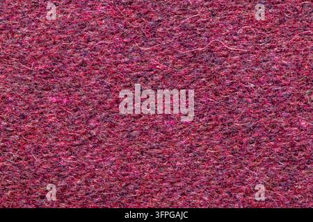 Photographie en gros plan d'un tissu de laine feutré présentant de riches fibres magenta et bordeaux sous un éclairage diffus doux. Banque D'Images