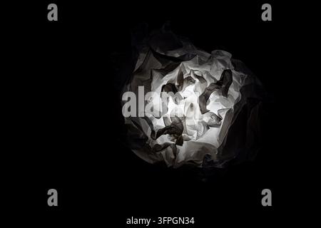 Objet lampe en papier froissé lumineux abstrait avec lumière et ombres isolé sur fond noir Banque D'Images