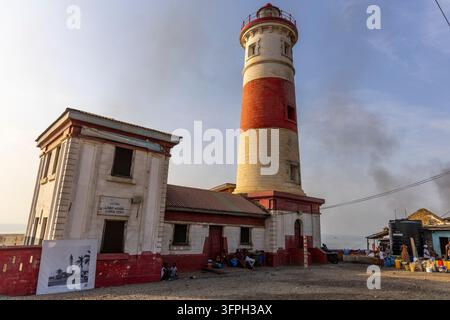 Phare James Town rayé rouge et blanc se dressant à côté d'un vieux bâtiment colonial avec des gens assis à l'extérieur, Grande Région d'Accra, Accra, Ghana Banque D'Images