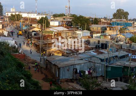 Vue élevée des toits en tôle ondulée et d'une allée nouvellement pavée avec des piétons dans la zone de Kibera au coucher du soleil, Nairobi County, Nairobi, Kenya Banque D'Images