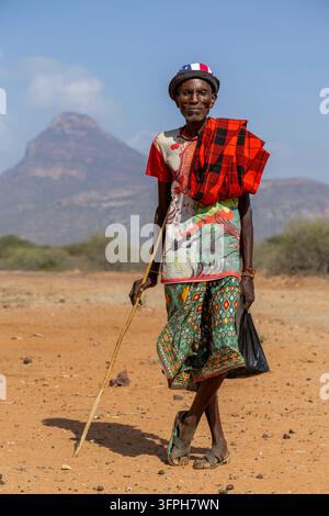Ancien homme de la tribu Samburu portant une chemise colorée et une shuka à carreaux rouges, appuyé sur une canne, comté de Samburu, Samburu, Kenya Banque D'Images