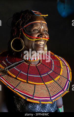 Femme souriante de la tribu Pokot aux cheveux tressés portant un collier de perles, des bandeaux perlés au visage et de grandes boucles d'oreilles en laiton, comté de Baringo, Churo, Kenya Banque D'Images