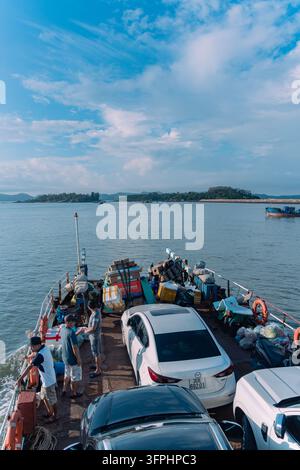 Passagers debout sur le pont d'une navette automobile chargé de voitures et de marchandises traversant la mer, port de Ghenh Vo, Quang Ninh, Vietnam Banque D'Images