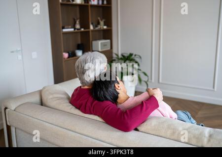 Couple de personnes âgées détendu et aimant s'embrassant et partageant un moment de paix en se relaxant ensemble sur le canapé. Banque D'Images