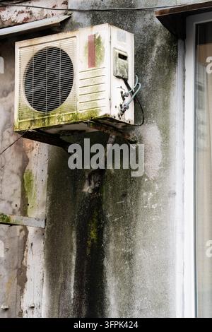 Ancienne unité de climatisation suspendue à un mur extérieur endommagé d'une maison résidentielle à Batumi, Géorgie. Banque D'Images
