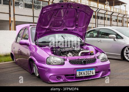 Vue avant d'une Chevrolet Corsa violette modifiée avec le capot ouvert, exposant son moteur et une suspension abaissée. Banque D'Images