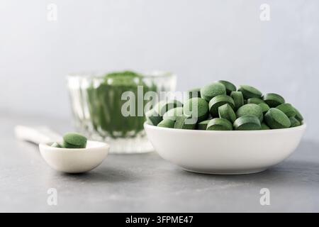 Chlorella ou spiruline sous forme de comprimés et de poudre sur un fond en béton gris. Banque D'Images