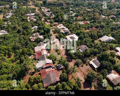 Vue aérienne de la plantation de caoutchouc de Chup présentant des rangées de arbres à caoutchouc, des maisons rurales avec des toits en métal et une route de terre à Tbong Khmum, Tboung Khmum, Cam Banque D'Images
