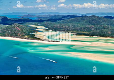 Vue aérienne de canaux de marée turquoise et de tourbillons de sable blanc, avec deux hors-bord au large, dans les Whitsunday Islands, Queensland, Australie Banque D'Images