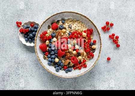 Bol de petit-déjeuner sain avec muesli d'avoine, baies fraîches, framboises, myrtilles, noix et groseilles rouges Banque D'Images