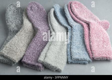 Une rangée douillette de chaussettes pastel moelleuses repose sur un fond clair, évoquant la chaleur, le confort et une sensation de détente hivernale douce. Banque D'Images