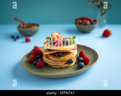 Stack de crêpes garni de fraises, framboises, myrtilles et fruits frais servis dans une assiette verte Banque D'Images