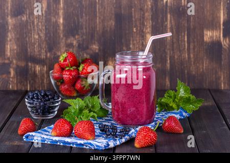 Alimentation saine, nourriture, régime et concept végétarien - smoothie à la fraise, myrtille et banane dans un mug en pot Mason, gros plan Banque D'Images