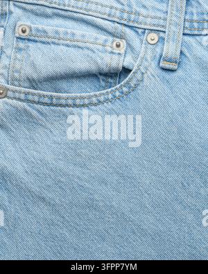 Close up d'une poche de jean bleu clair avec coutures et rivets visibles, montrant la texture des vêtements décontractés et les détails de mode. Banque D'Images