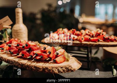 Brochettes de fruits frais servies sur des planches en bois rustiques à un buffet Banque D'Images
