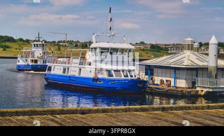 Un bateau ferry de Shields quitte South Shields sur l'estuaire de la Tyne, en Angleterre, le 23 juin 2026, tandis qu'un autre bateau reste hors service amarré au dépôt Banque D'Images