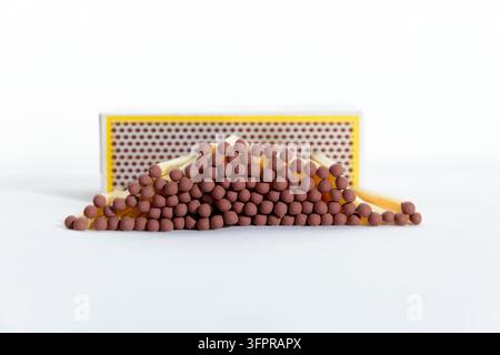 Photographie en gros plan en studio d'une pile d'allumettes en bois inutilisées avec des têtes brunes posées devant une bande d'allumage en nid d'abeille d'une boîte d'allumettes sur un isolat Banque D'Images