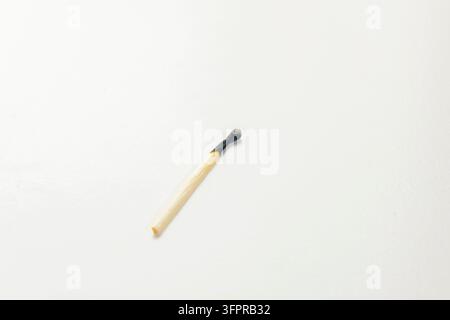 Photo en gros plan d'une allumette en bois brûlée éteinte reposant sur un fond blanc propre. Banque D'Images