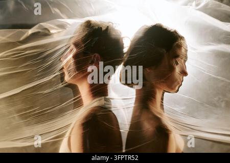 Homme et femme debout dos à dos derrière un film plastique Banque D'Images